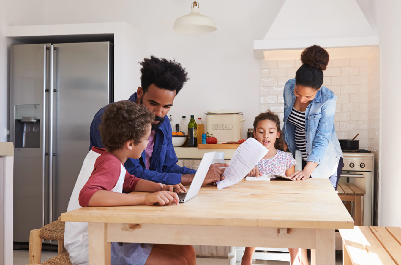 Family all working on a laptop in a kitchen