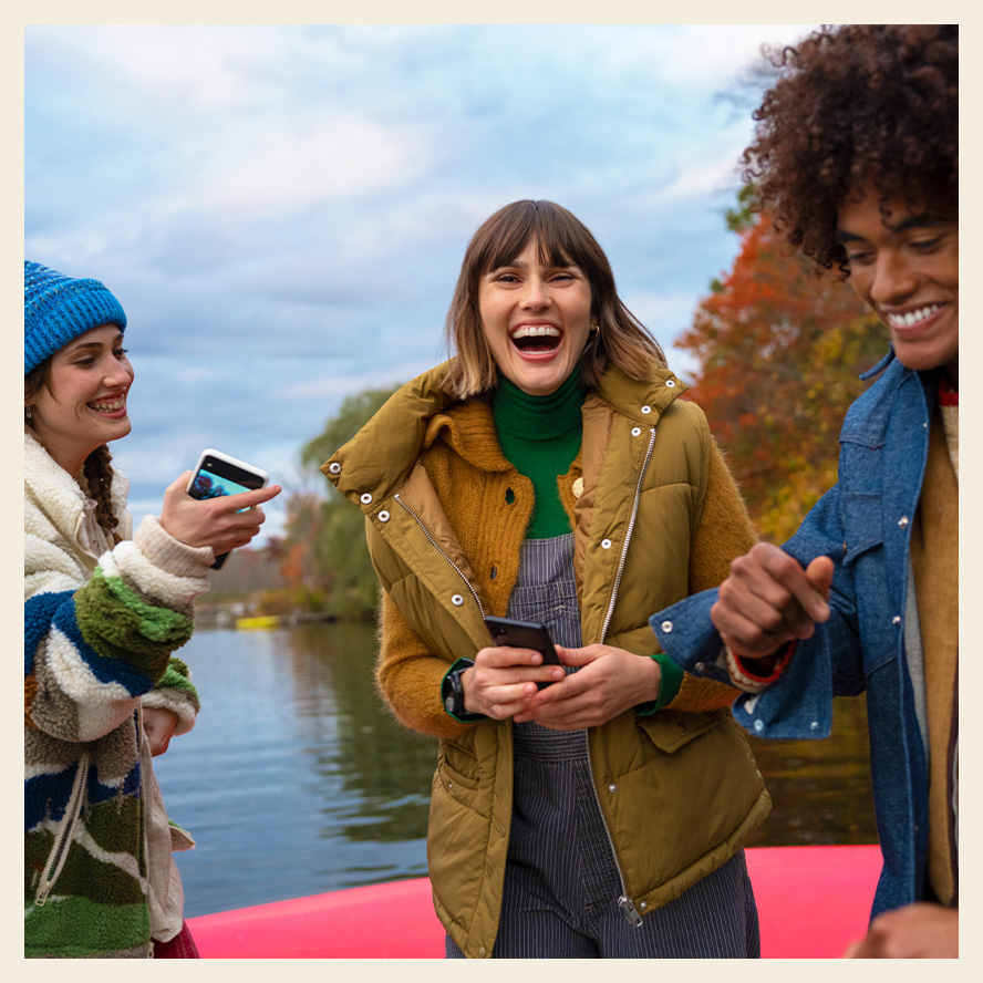 three girls laughing with smartphones in their hands