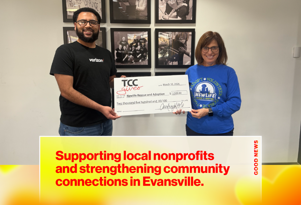 Two people hold a large donation check labeled to Newlife Rescue and Adoption during a community event.