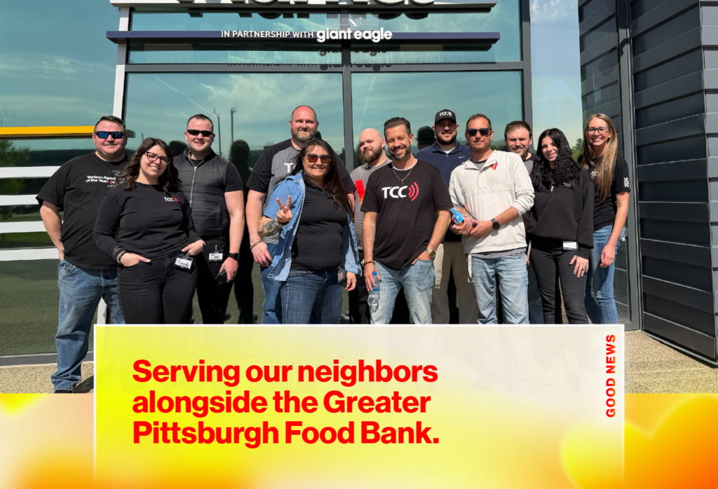 Group of volunteers posing outside a building, with a large banner that reads “Serving our neighbors alongside the Greater Pittsburgh Food Bank.”