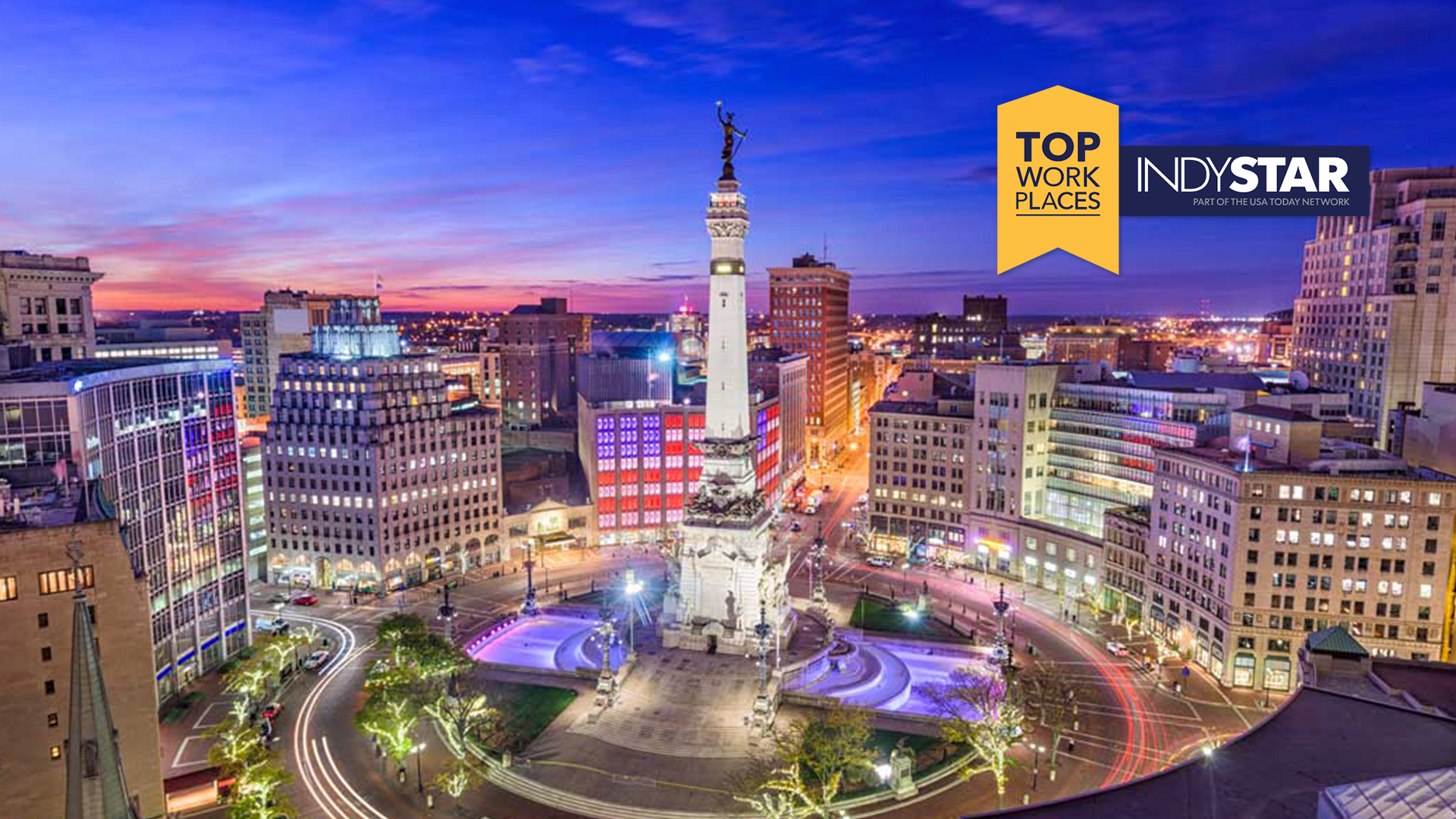 Evening aerial view of downtown Indianapolis with Monument Circle, featuring the Top Work Places badge and the IndyStar logo